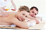 Positive young couple receiving a back massage with oil in a health spa