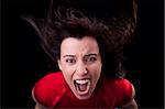 beautiful young woman with her hair in the wind, screaming in fury, isolated in black. Studio shot.