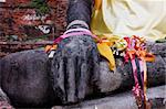 Stone hand of Buddha covered by gold fabric from the temple