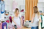 Friendly saleswoman packing clothes in a bag  in a clothes store