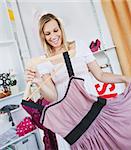 Cheerful young woman holding a dress in a clothes store