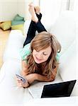 Radiant caucasian woman on the sofa with laptop and card  in the living room