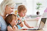 Astonished children looking at a laptop with their mother at home