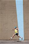 Muscular man practices for a race in front of concrete wall