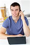 Attractive man talking on phone looking at the camera at home