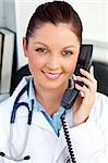 Smiling female doctor talking on phone in her office