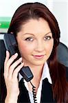Positive businesswoman phoning in her office at her desk