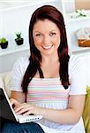 cheerful woman working with her laptop sitting at home smiling at the camera