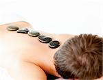 Young caucasian relaxing man with hot stone on his back in  a spa center