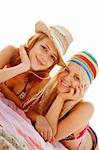 Two beautiful young girlfriends in bikini on the beach at sunrise. Photo with counter-light on background.