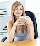 Glowing businesswoman holding a cup at her desk in her office