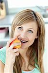 Captivating caucasian woman eating an apple in the kitchen at home