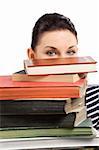 close up portrait of young and cute brunette student hiding her face behind a pile of books