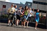 Happy group of business people running on city street