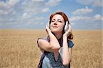 Young  smiling girl with headphones at wheat field.
