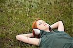 Young  fashion with headphones lying at green grass.