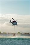 Fire brigade helicopter hovering over water while refilling the tank