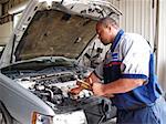 Auto mechanic checking radiator levels while performing a routine service inspection in a service garage.