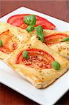 Puff pastry with cheese and tomatoes seasoned with sesame seeds