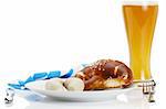 bavarian veal sauages on a plate with beer, pretzel and bavarian towel on white background