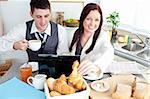 Couple of businesspeople using a laptop during their breakfast at home