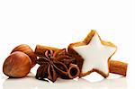 star shaped cinnamon biscuit with cinnamon sticks and hazelnuts on white background