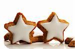 two standing star shaped cinnamon biscuits on white background