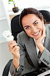 Beautiful businesswoman holding a light bulb in her office