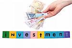 toy letters that spell house investment with cash in hand against a white background with clipping path