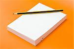 blank book and pencil over an orange background