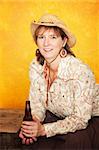 Pretty western woman in cowboy shirt and hat with beer bottle