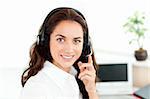 Pretty hispanic businesswoman with headset sitting at her desk in a call center