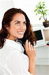 Attractive businesswoman holding glasses and sitting at her desk in her office