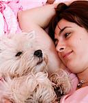 Westie sleeping next to woman in bed .