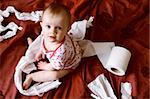 Down shot of naughty surprised baby found tearing up toilet roll