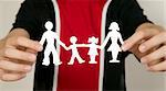 Child with black and red shirts is holding family figures made from paper