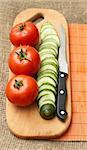 Cooking: tomatoes, cucumber and knife on kitchen board