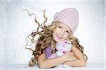 winter fashion cap little girl hug teddy bear smiling silver background