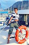 Boy teen sailor mooring boat rope in harbor summer marina standing up