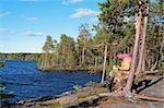 The tourist reading the book on rocky coast of blue lake