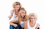 three young women sitting on the floor, looking up- isolated on white