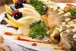 Stuffed baked fish served with lemon and salad