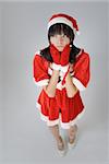 Cute Christmas girl with funny expression against gray background.