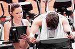 Exhausted man doing exercises while his coach is looking at his results in a sport centre