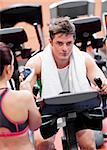 Female coach using a chronometer while man is doing physical exercises in a fitness centre