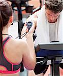 Close-up of a coach using a chronometer while man is doing physical exercises in a fitness centre