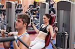Concentrated couple using shoulder press in a fitness centre