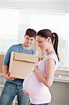 adorable future mother with husband standing in their new house unpacking in the kitchen