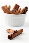 Closeup of a bowl with cinnamon sticks on white background. Shallow dof