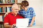 Little boy helping his middle-aged father use the computer.